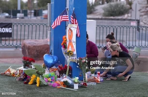 People light candles, place figures and flowers at a makeshift memorial set up under the "Welcome to Faboulous Las Vegas" sign for the Las Vegas mass...