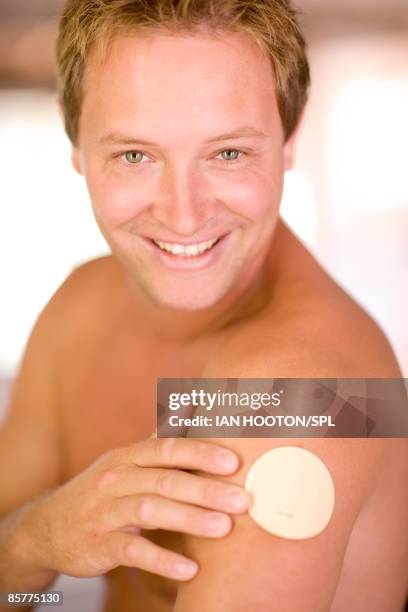 mid adult man wearing nicotine patch on arm, smiling, close-up - transdermal patch stock pictures, royalty-free photos & images