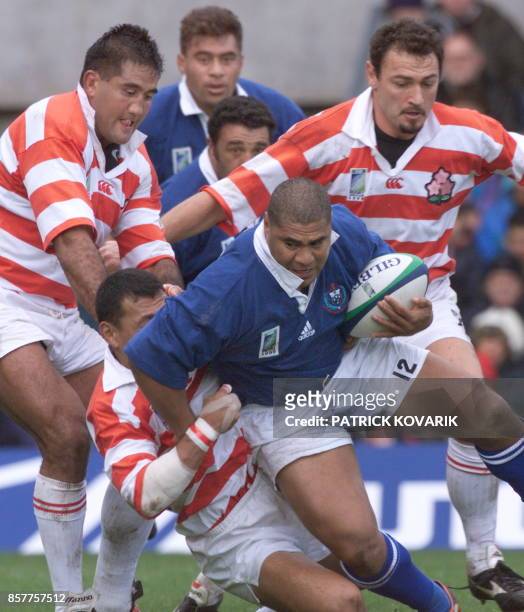 Samoan centre Va'aiga Tuigamala tries to break away from the tackle of Japanese Jamie Joseph and Greg Smith during the Rugby World Cup first-round...