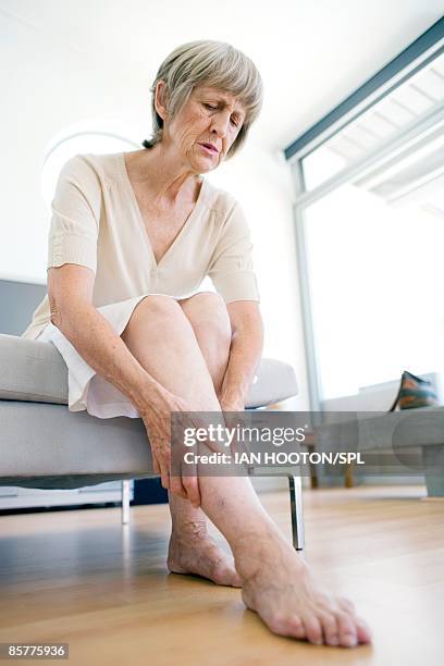 woman rubbing aching leg - old lady feet stockfoto's en -beelden