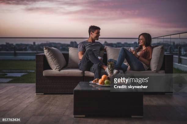 happy couple relaxing on a patio at twilight and communicating. - coffee on patio stock pictures, royalty-free photos & images