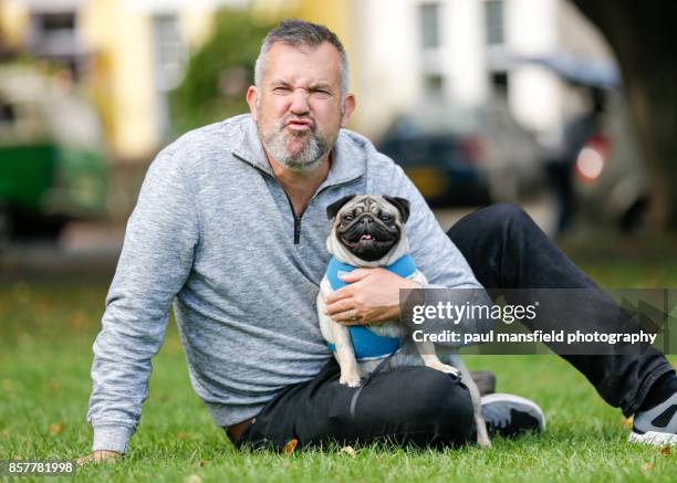 mature man making a funny face whilst sitting with his pet dog - snorted stock pictures, royalty-free photos & images