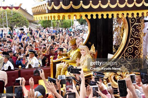 Brunei's Sultan Hassanal Bolkiah and Queen Saleha wave to people as they march through Brunei's capital Bandar Seri Begawan on Oct. 5 to mark 50...