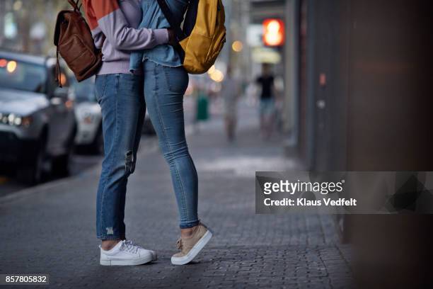 lesbian couple, with backpacks, hugging on the street - human limb stock pictures, royalty-free photos & images