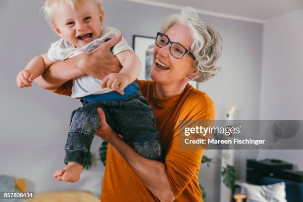 grandmother happily lifting up her joyful baby grandchild - raising baby stock-fotos und bilder