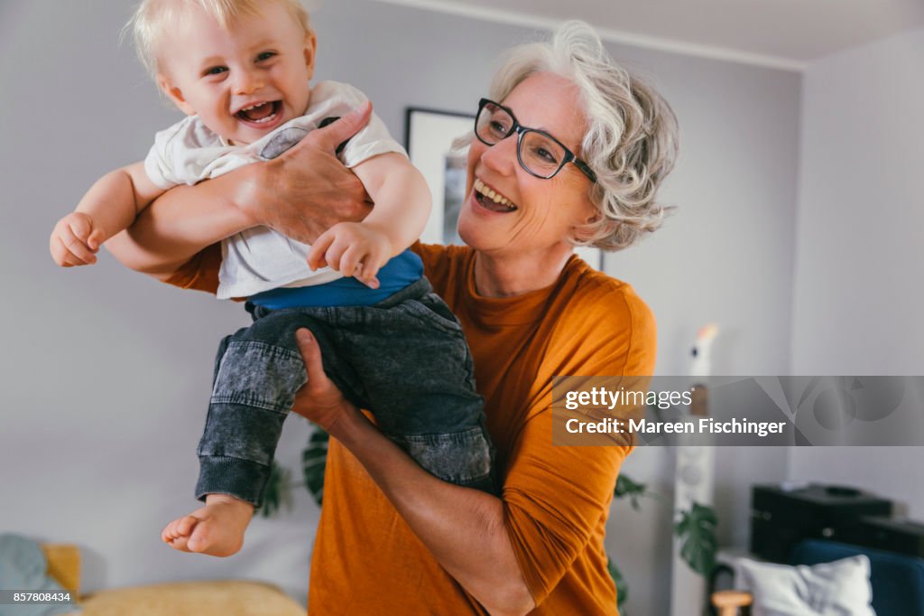Grandmother happily lifting up her joyful baby grandchild