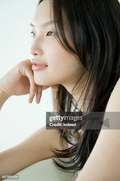 japanese woman looking away, hand on chin - ミディアムヘア ストックフォトと画像