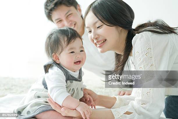 parents smiling and looking at baby girl - japanese baby photos et images de collection
