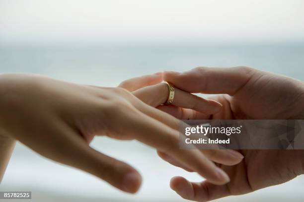 man placing ring on woman's finger - bague photos et images de collection