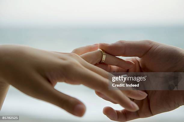 man placing ring on woman's finger - 結婚戒指 個照片及圖片檔