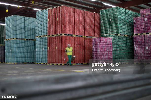 An employee passes pallets stacked with soft-drink cans ahead of shipping at the Refresco Group NV beverage bottling factory in Maarheeze,...