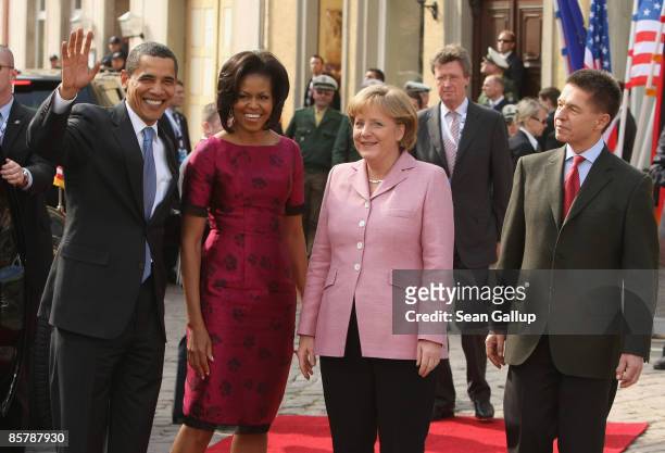 President Barack Obama and his wife Michelle wave upon their arrival as German Chancellor Angela Merkel and her husband Joachim Sauer look on before...