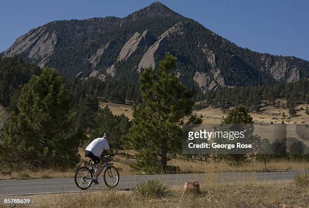 Bicyclist peddles up Table Mesa Road with the Flatiron rock formation as a backdrop as seen in this 2009 Boulder, Colorado, spring landscape photo.