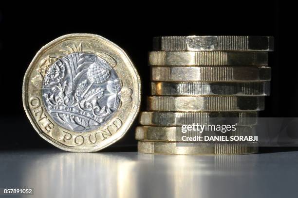 British one pound sterling coins are arranged for a photograph in central London on October 5, 2017. - The British pound was under pressure on...