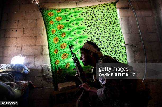 Member of the Syrian Democratic Forces , Syrian fighters backed by US special forces, takes a position inside a building on the eastern frontline of...