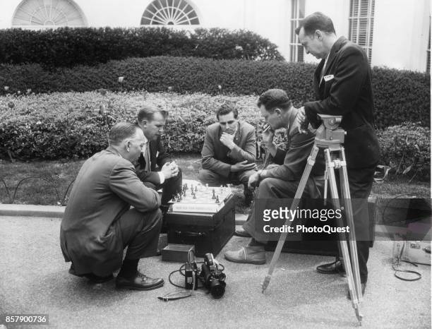 On the White House driveway, members of the White House press corps play a game of chess on an equipment case during a break, Washington DC, April...