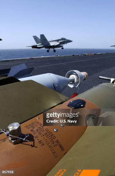 Five hundred pound GBU-12 laser-guided bombs are readied on the flight deck as an F/A-18 "Hornet" launches from one of the ship's four steam...