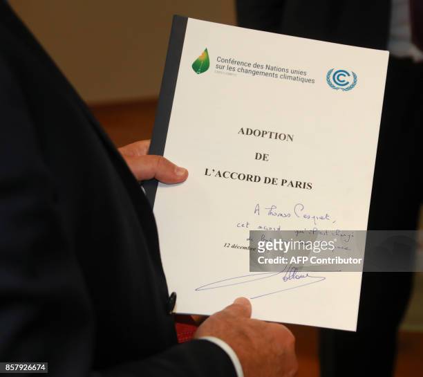 Former French President François Hollande holds a copy of the 196-nation Paris Agreement on Climate, that he handed to French astronaut Thomas...