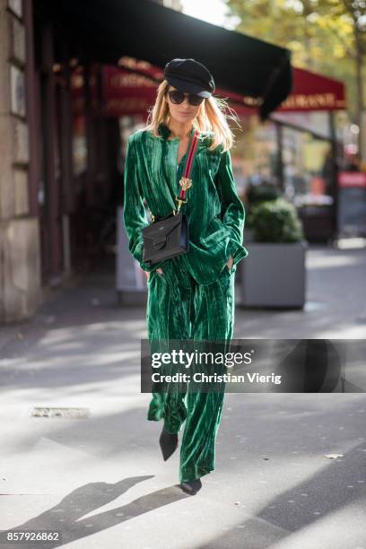 Gitta Banko wearing a green velvet suit by Jadicted, white cotton shirt by Dsquared 2, black sock boots from Mango, a Suzy suitcase handbag made of...