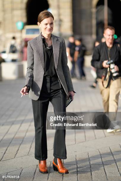 Guest wears a checkered blazer jacket, a black top, black flare pants, brown leather shoes, outside Louis Vuitton, during Paris Fashion Week...