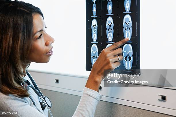 african american female doctor looking at x-ray - lightbox stock pictures, royalty-free photos & images