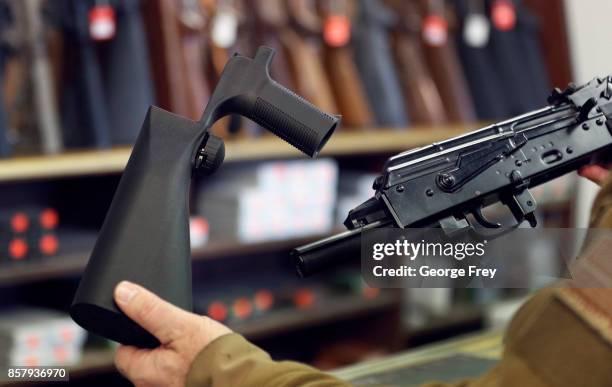 Bump stock device , that fits on a semi-automatic rifle to increase the firing speed, making it similar to a fully automatic rifle, is shown next to...