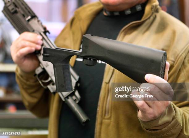 Bump stock device , that fits on a semi-automatic rifle to increase the firing speed, making it similar to a fully automatic rifle, is shown next to...