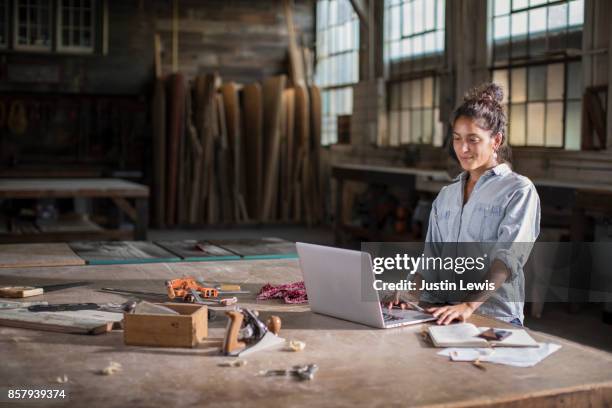 young mixed race female entrepreneur solving a complicated business challenge with pencil, laptop, carpentry tools, and confidence - filipino ethnicity and female not male fotografías e imágenes de stock