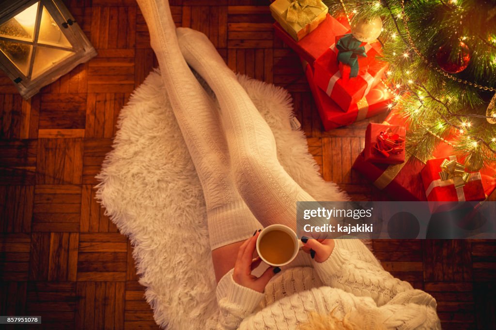 Ung kvinna dricka varmt kaffe på julnatten