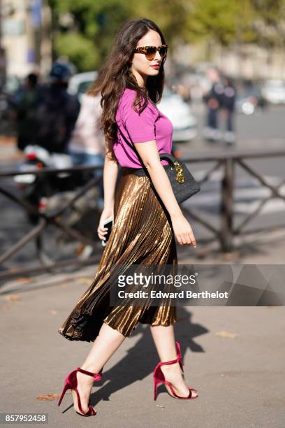 Guest wears sunglasses, a pink t-shirt, a golden pleated shiny skirt, red heels shoes, outside Miu Miu, during Paris Fashion Week Womenswear...