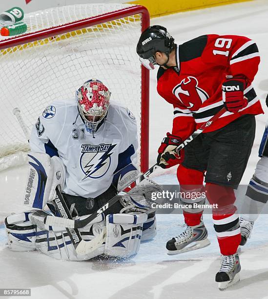 Karri Ramo of the Tampa Bay Lightning makes the stop on Travis Zajac of the New Jersey Devils on April 3, 2009 at the Prudential Center in Newark,...