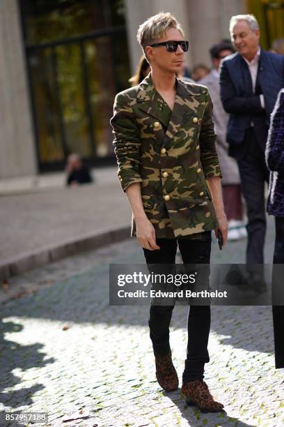 Guest wears sunglasses, a military camouflage print jacket, pants, brown shoes , outside Miu Miu, during Paris Fashion Week Womenswear Spring/Summer...