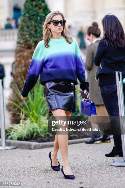 Guest wears sunglasses, a blue and green pull over, a black vinyl skirt, shoes, outside Moncler, during Paris Fashion Week Womenswear Spring/Summer...