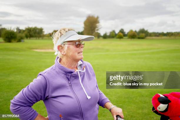 a senior woman on the golf course, with her parrot club protector. - golf driver stock pictures, royalty-free photos & images