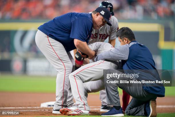 Manager John Farrell and trainer Masai Takahashi tend to Eduardo Nunez of the Boston Red Sox after he was injured while running up the first base...