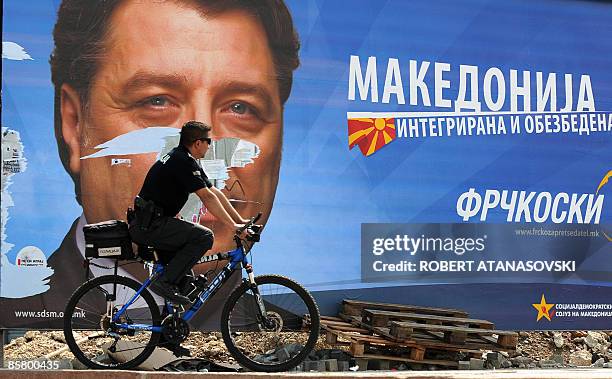 Cyclist rides his bike as he passes a large election billboard of the opposition SDSM party Ljubomir Frckoski in Skopje on April 4, 2009. Macedonians...