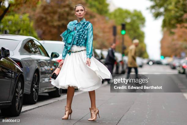 Landiana wears a blue lace ruffle top, a white skirt, heels shoes, outside Valentino, during Paris Fashion Week Womenswear Spring/Summer 2018, on...