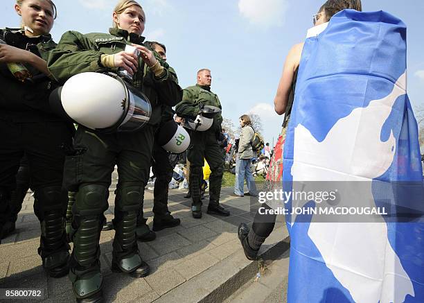 An anti-NATO activist wrapped in a dove flag stands next to riot police officers during an anti-NATO protest in Kehl on April 4, 2009. Thousands of...