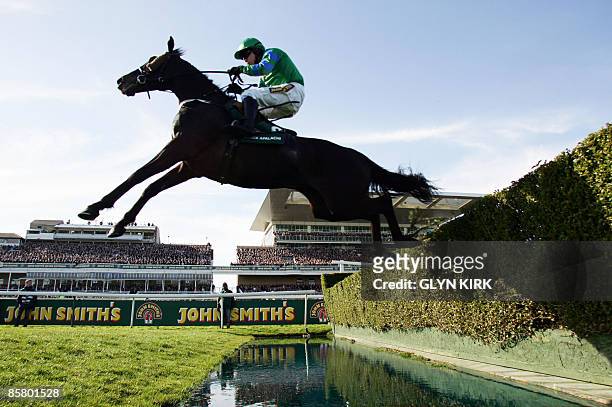 Denis O'Regan rides BLACK APALACHI over the water jump during The John Smith's Maghull Novices' Steeple Chase on the third day of the Grand National...