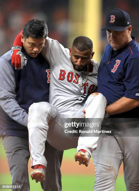 Eduardo Nunez of the Boston Red Sox is carried off the field by Red Sox trainer Masai Takahashi and manager John Farrell after suffering an injury in...