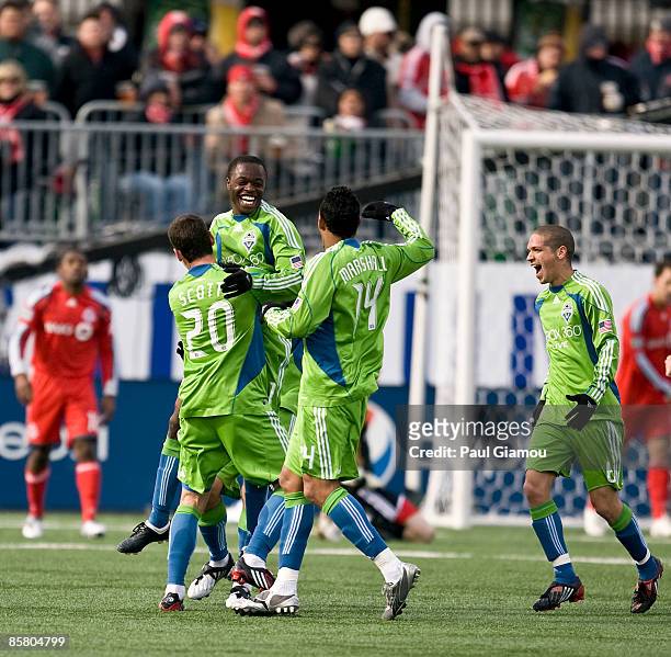 Midfielder Steve Zakuani is embraced by defender Zach Scott, defender Tyrone Marshall, and midfielder Osvaldo Alonso of the Seattle Sounders during...