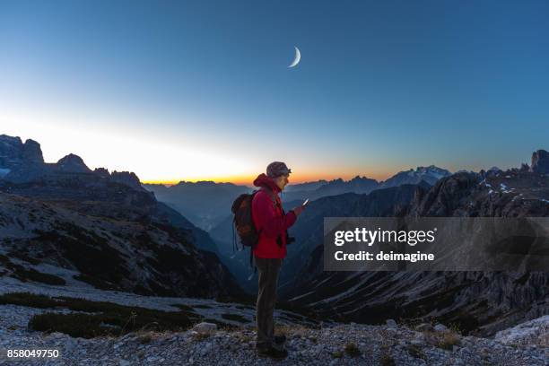 wanderer auf der suche karte auf gerät - bergsteiger mit karte und rucksack stock-fotos und bilder