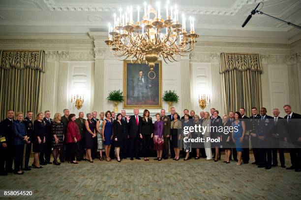 President Donald Trump and first lady Melania Trump pose for pictures with senior military leaders and spouses after a briefing in the State Dining...