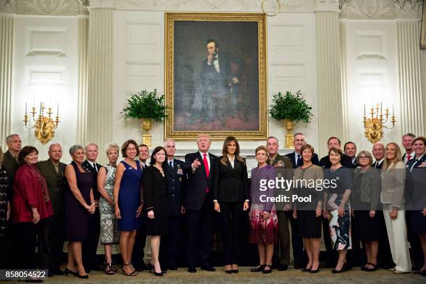 President Donald Trump and first lady Melania Trump pose for pictures with senior military leaders and spouses after a briefing in the State Dining...
