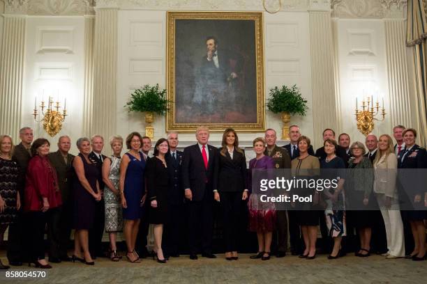 President Donald Trump and first lady Melania Trump pose for pictures with senior military leaders and spouses after a briefing in the State Dining...