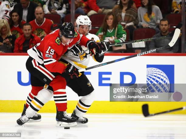 Jonathan Toews of the Chicago Blackhawks and Sidney Crosby of the Pittsburgh Penguins battle for the puck during the season opening game at the...