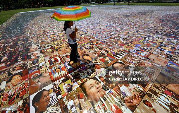 Visitor looks at a photo mosaic of Philippine President Gloria Arroyo set up at Luneta park in Manila on April 5, 2009. Supporters of Philippine...