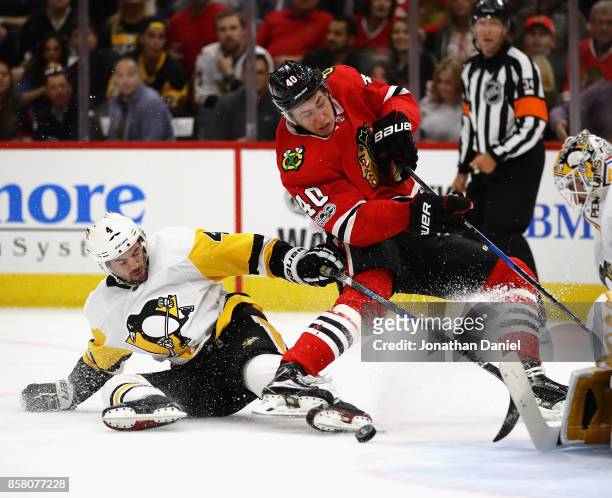 John Hayden of the Chicago Blackhawks is tripped while shooting by Justin Schultz of the Pittsburgh Penguins during the season opening game at the...