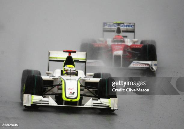 Race winner Jenson Button of Great Britain and Brawn GP leads from third placed finisher Timo Glock of Germany and Toyota during the rain curtailed...