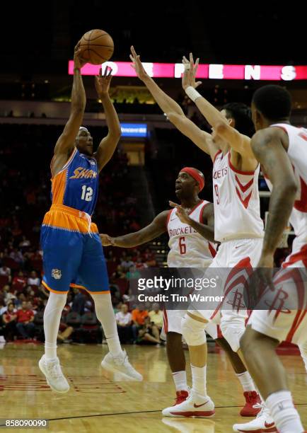 Josh Akognon of Shanghai Sharks passes the ball defended by Bobby Brown of Houston Rockets and Zhou Qi in the second half at Toyota Center on October...
